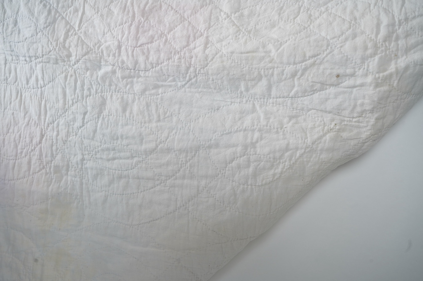 A 1900-1910 English, possibly north country hand quilted bedcover. Designed with a large central medallion, hand quilted using mostly pastel patterned and plain cottons and feature red and black cottons as highlights, ba